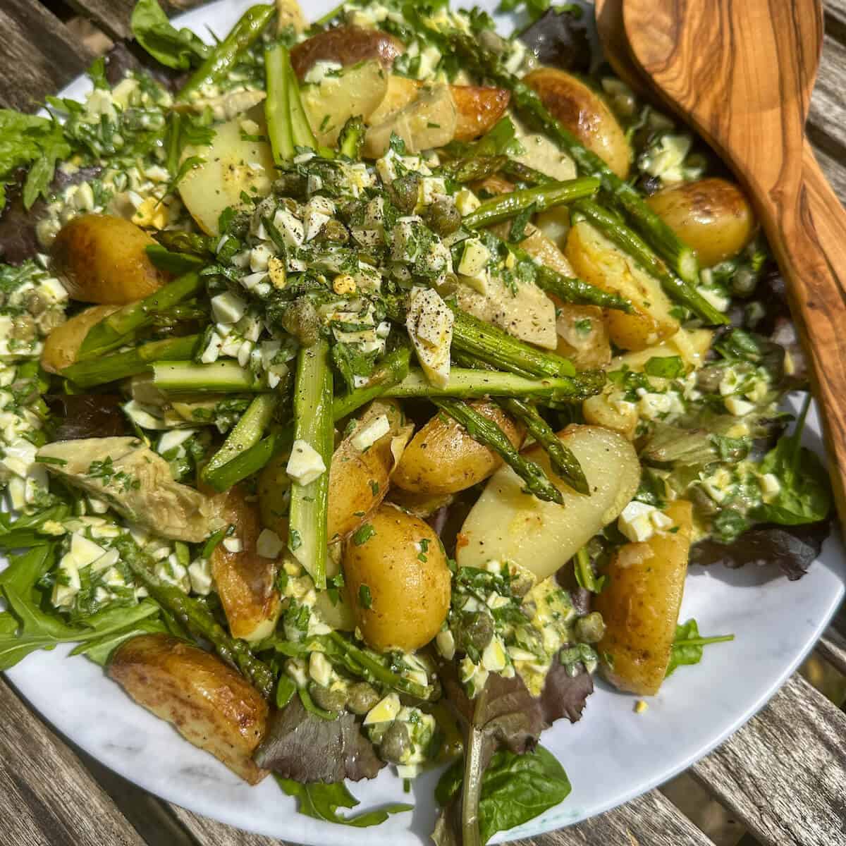 A summer salad of asparagus, potato and artichoke on a bed of leaves with a sauce gribiche. 
