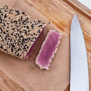 Sesame crusted tuna akami on a chopping board with a knife.