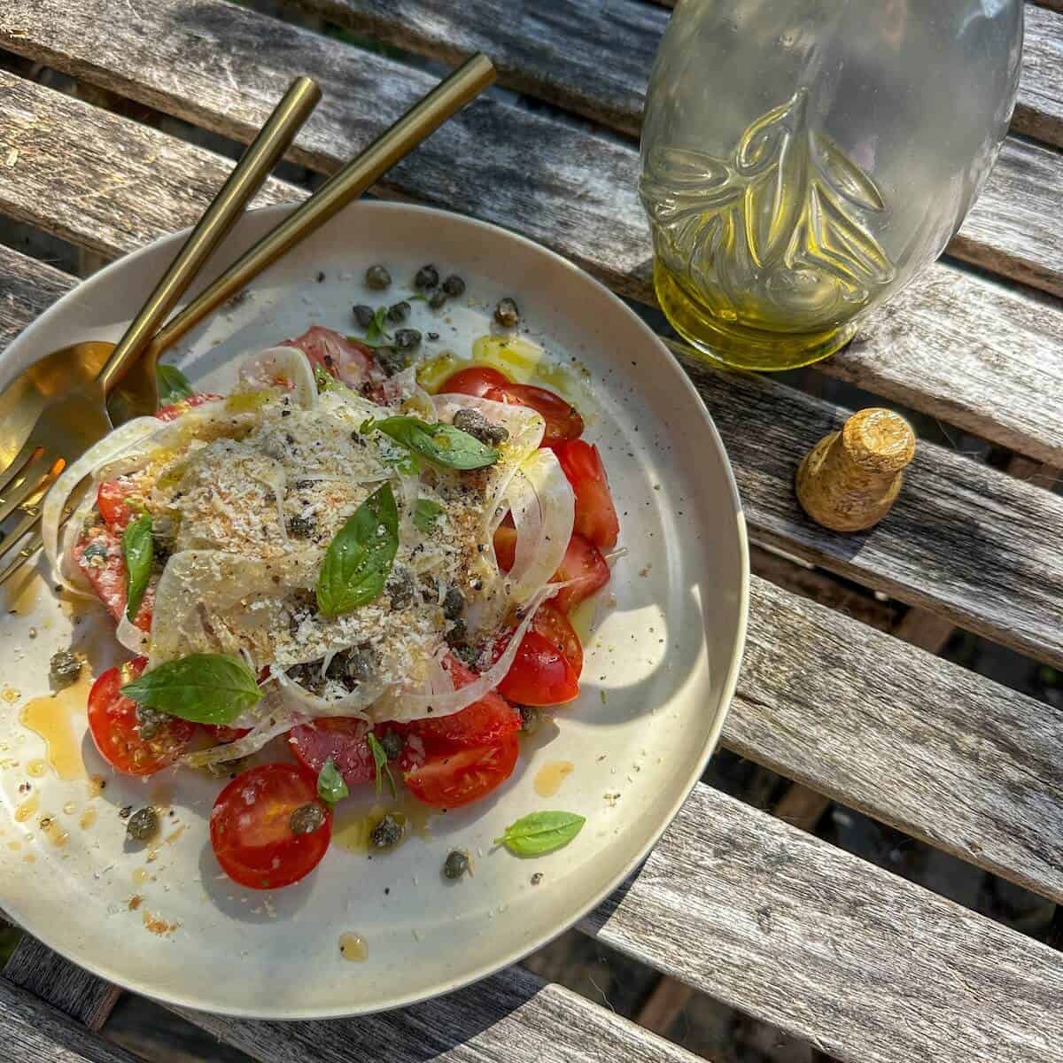 A plate of fennel tomato salad with colatura di alici , panko, basil and capers.