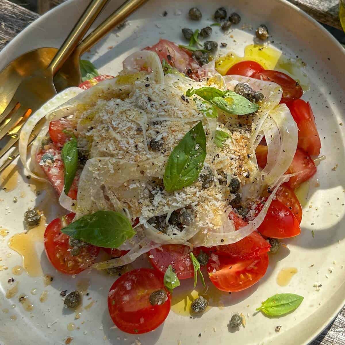 Fennel tomato salad on a plate with panko breadcrumbs, basil and capers.