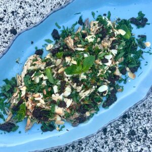 Fire roasted tinned fish on a platter with herbs, olives and almonds.