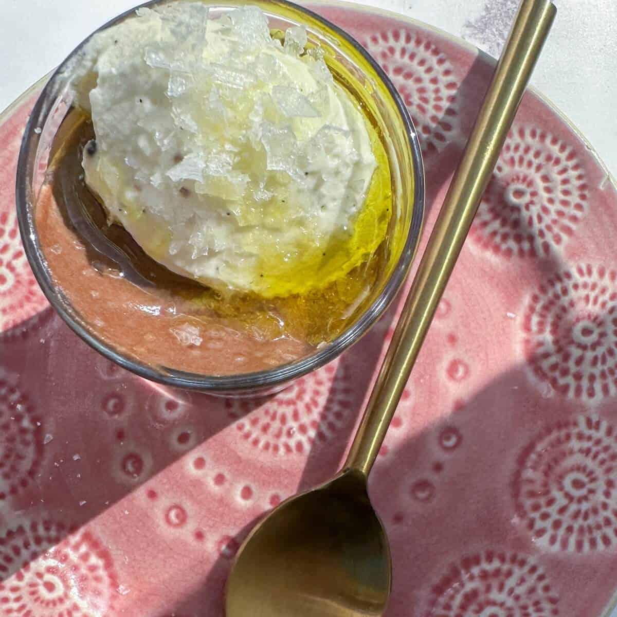 A glass of chocolate mousse made with olive oil and topped with cardamom Chantilly cream and sea salt.