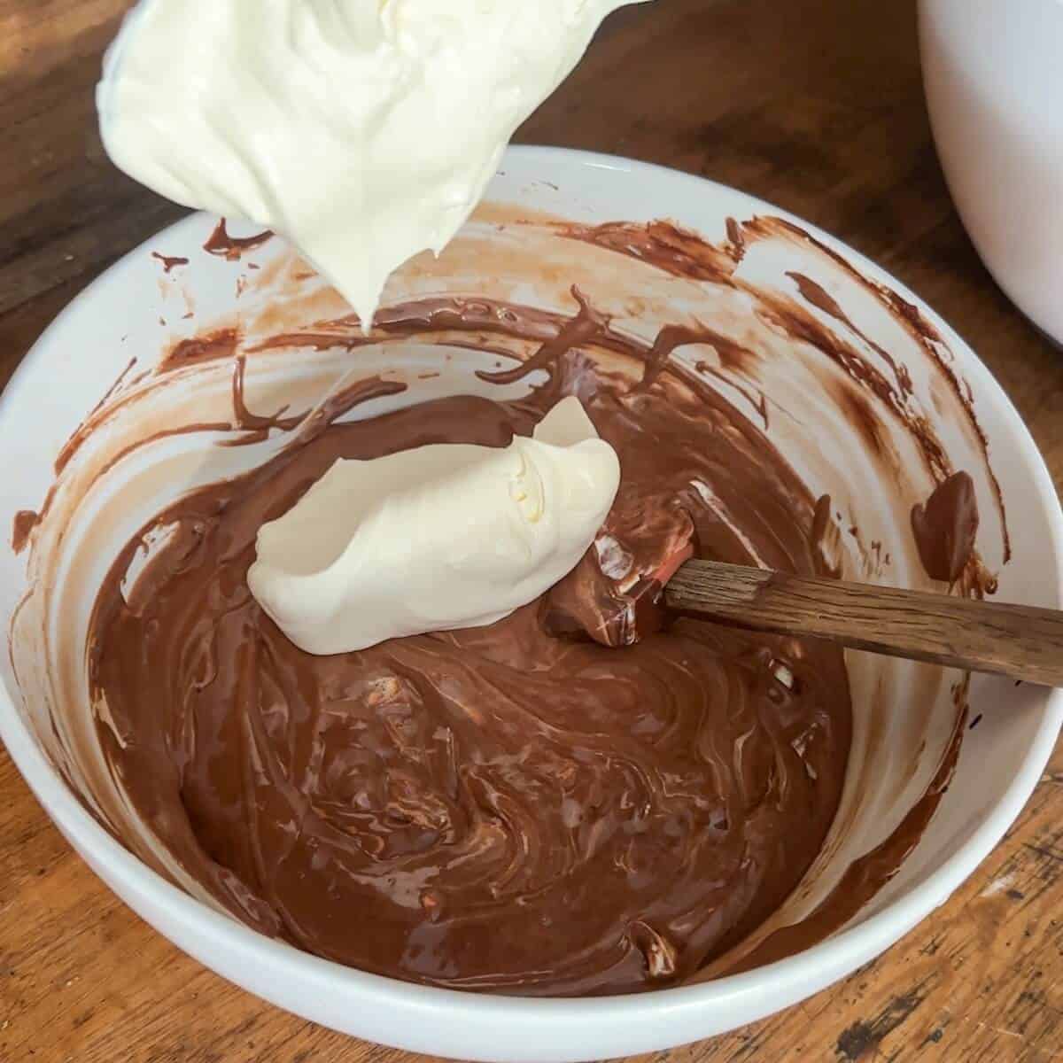 Whipped cream being folded into chocolate olive oil mousse.