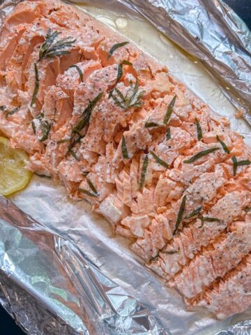 A whole side of salmon en papillote sliced up into individual portions.