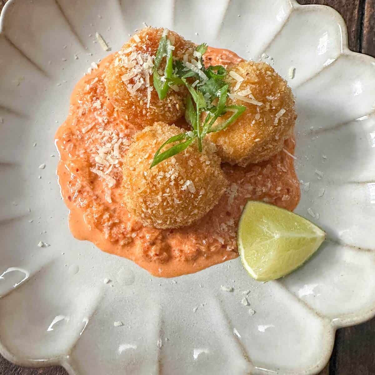 Three gochujang arancini balls on a plate.