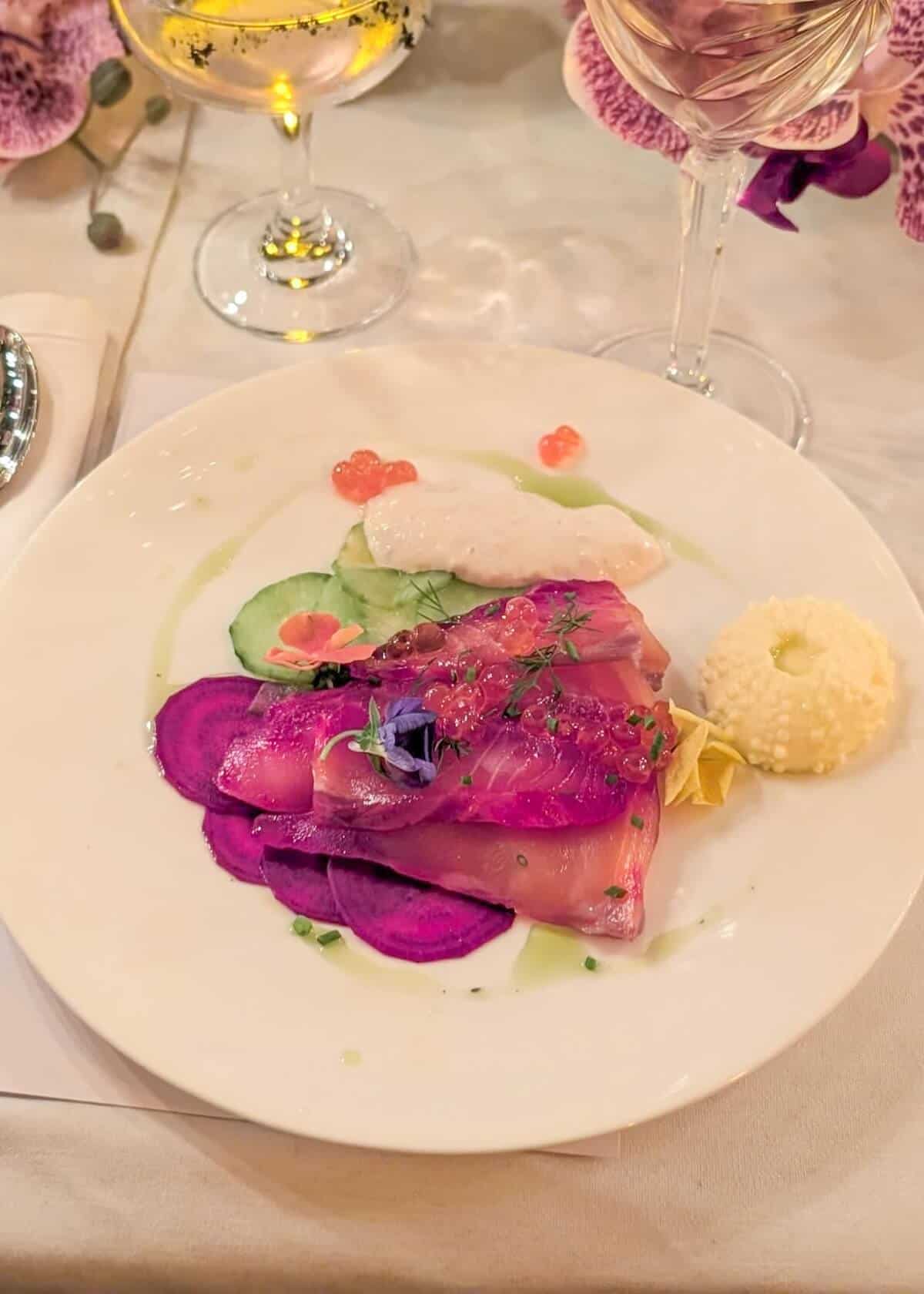 A stylish plate of beetroot gravadlax wiith caviar, edible flowers, and thinly sliced beetroot.