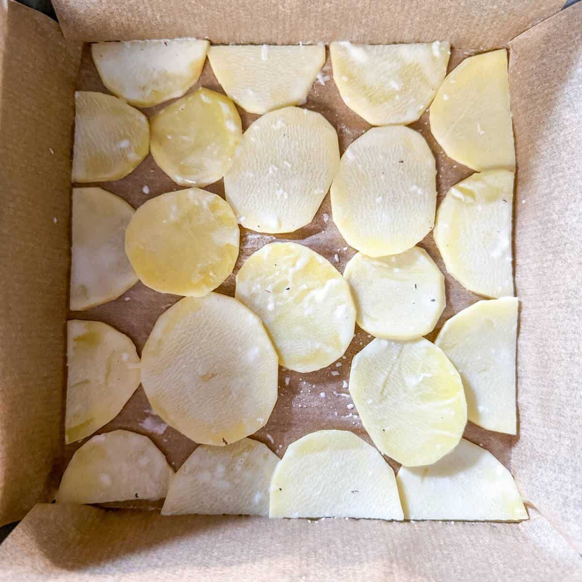A baking pan filled with slices of potato to make a dauphinoise.
