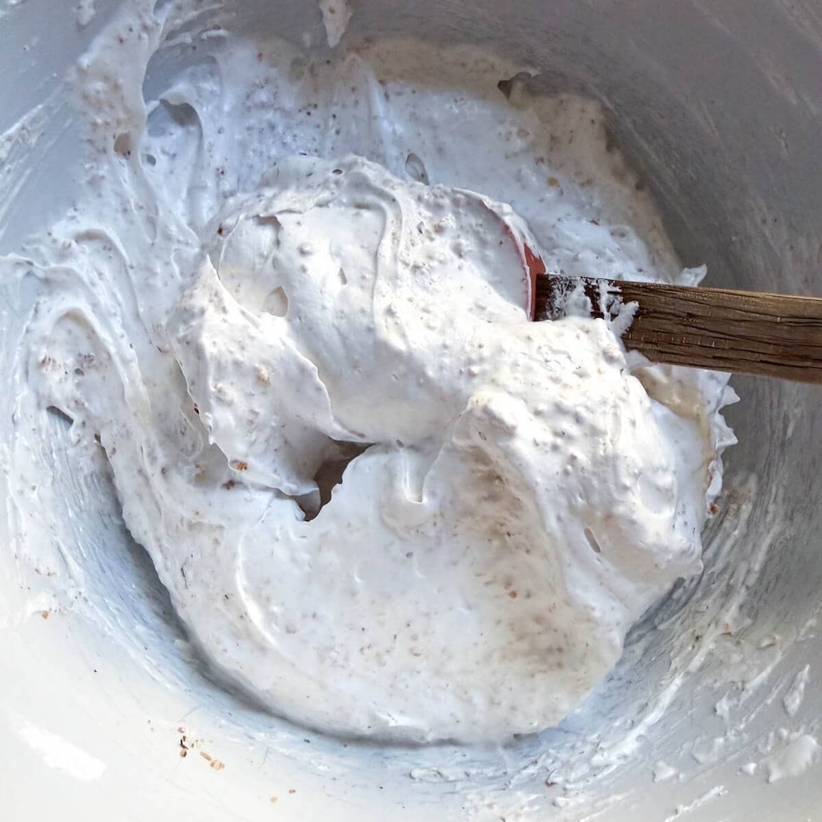 Meringue mixed with ground toasted hazelnuts in a bowl.