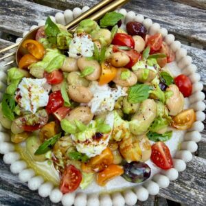 A plate of butterbean caprese salad with olives, tomato and mozzarella.