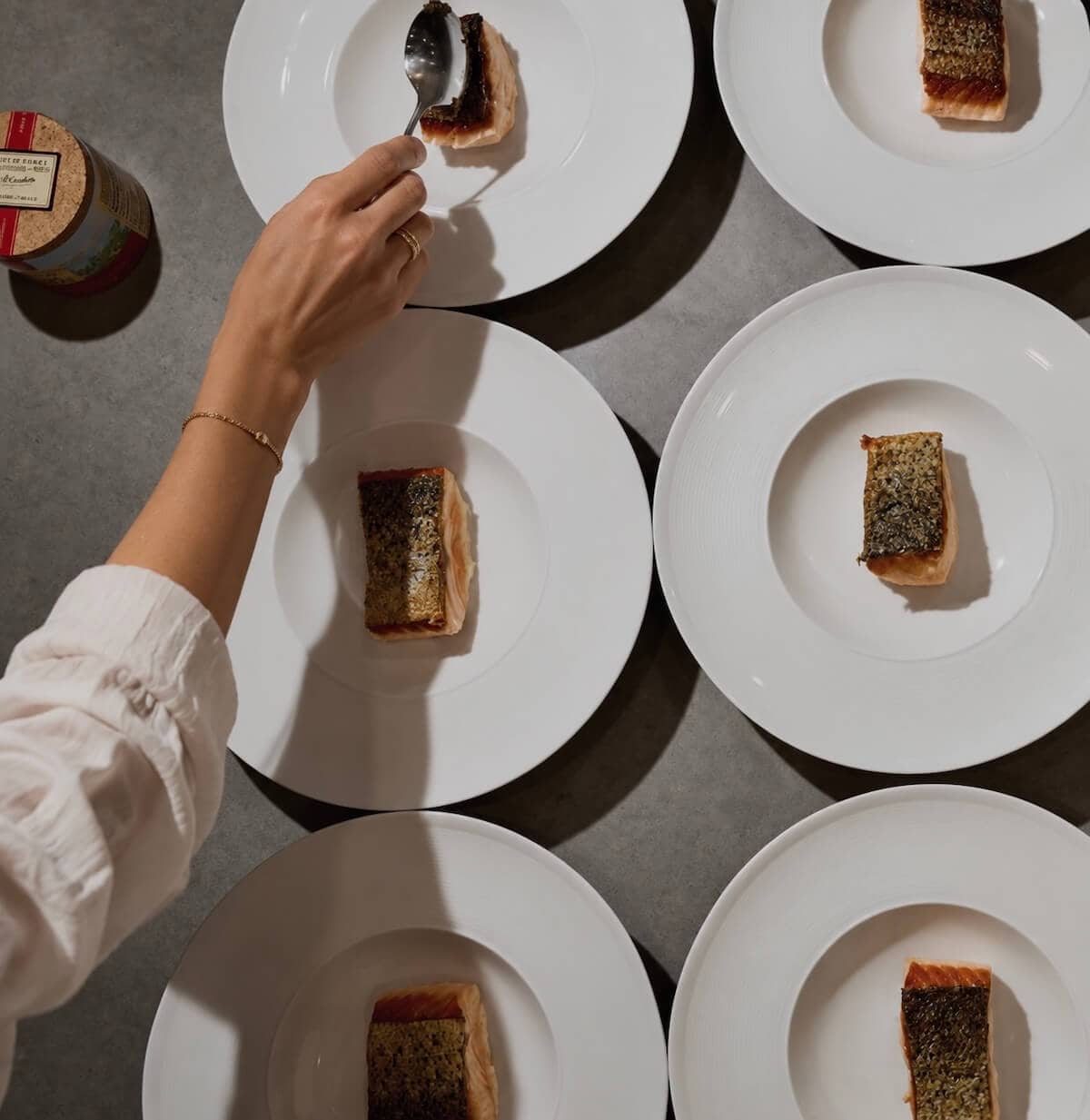 A photo of a woman plating up food for a dinner party.